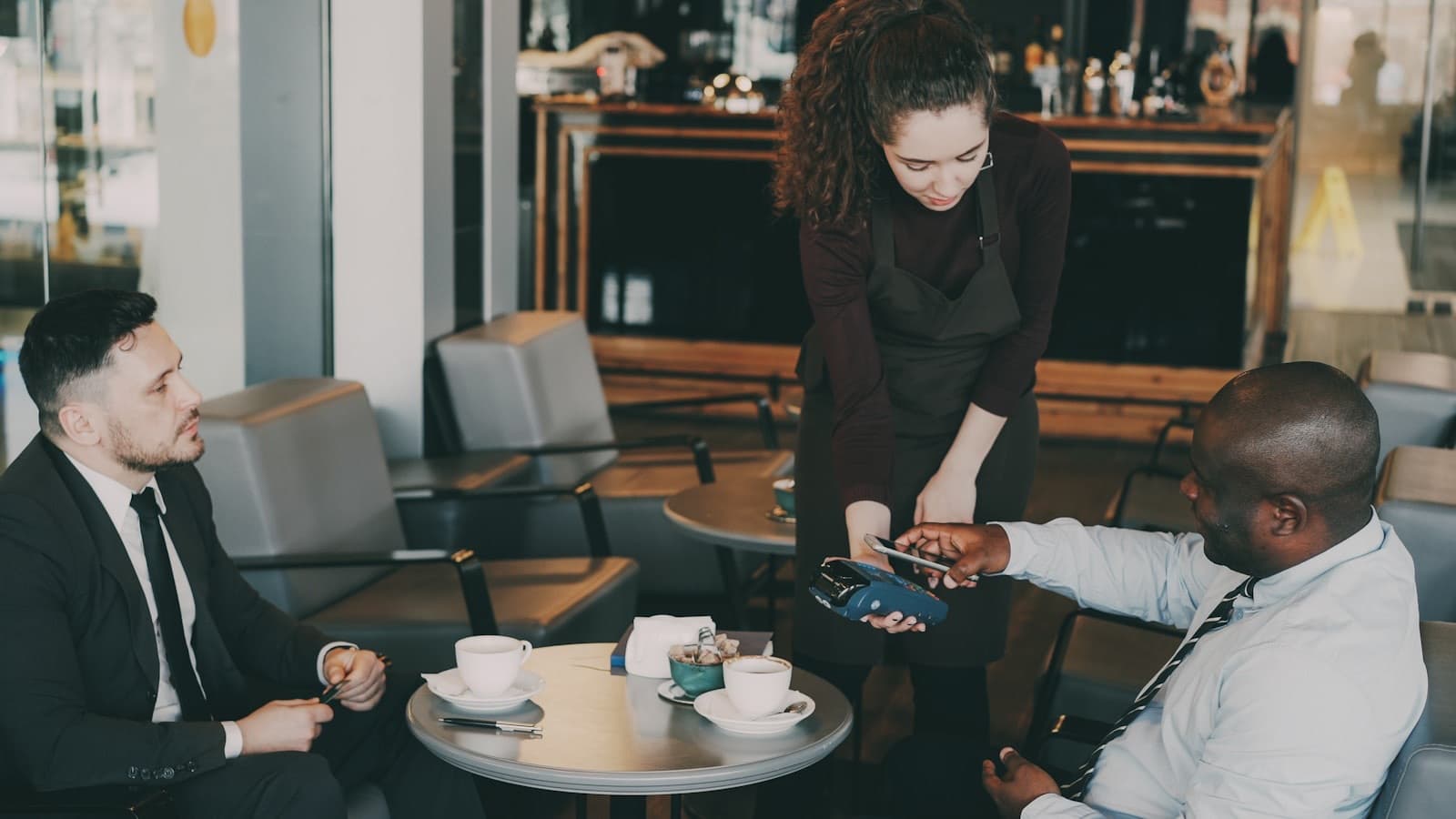 A customer paying by card in a busy cafe